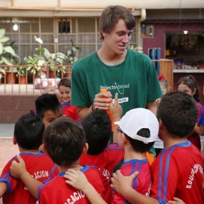A volunteer and the kids around him during sport practice in Costa Rica Children in Costa Rica around a Projects Abroad volunteer during a sport practice